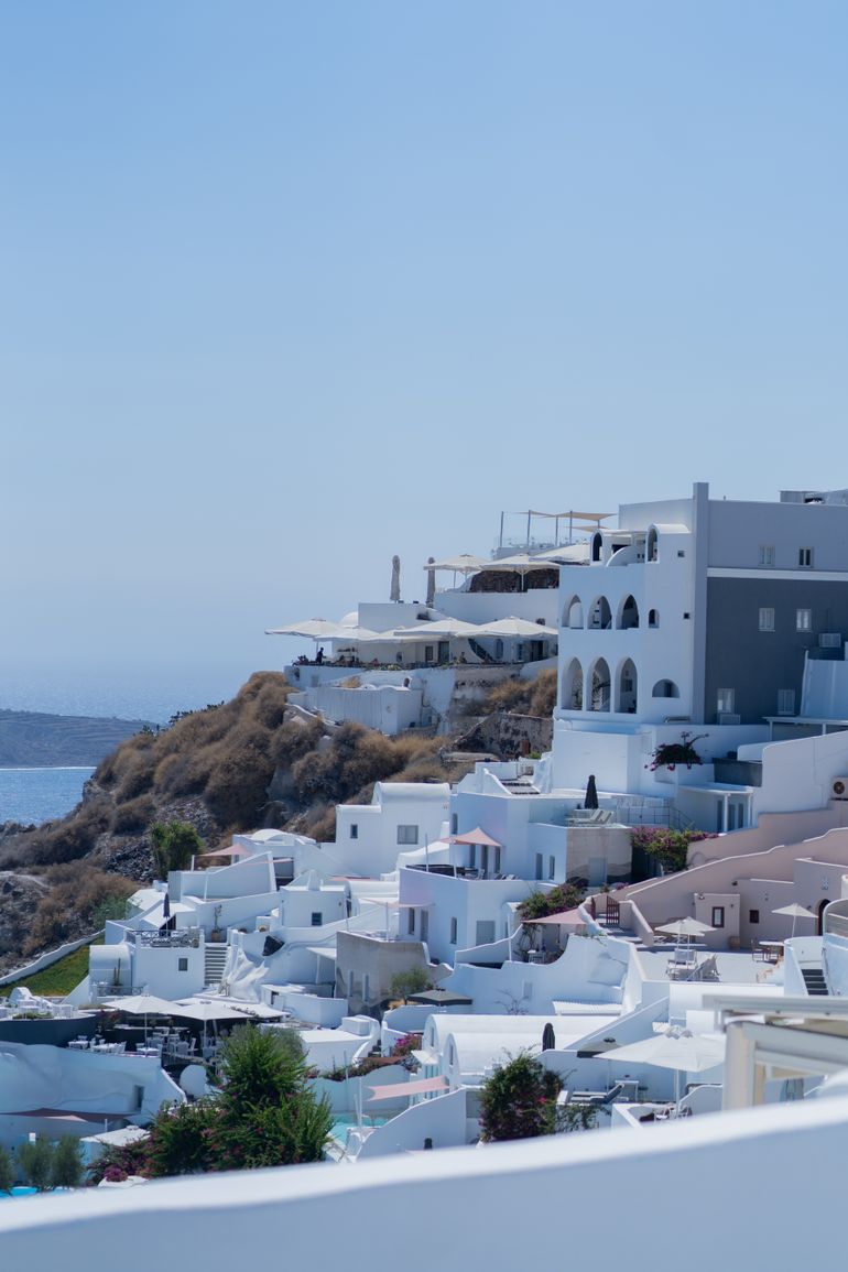 View of Santorini's whitewashed buildings overlooking the Aegean Sea, under a bright blue sky.